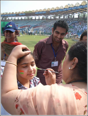 A boy gets his face painted with the Indian and Pakistani flags.